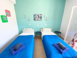 two beds in a room with blue walls at Avra Budget Beach Rooms in Benitses