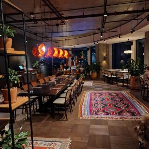 a dining room with tables and chairs and a rug at Holiday Lux Tower in Batumi