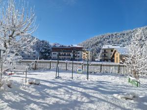 een sneeuwbedekte tuin met een hek en gebouwen bij Residenze Macerelli in Roccaraso