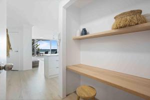 a kitchen with white walls and a wooden shelf at Beachfront Luna Apartment in Gold Coast