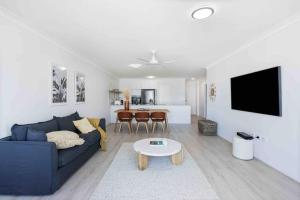 Beachfront Luna Apartment في غولد كوست: غرفة معيشة مع أريكة زرقاء وطاولة