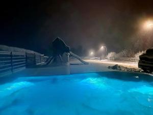 bañera de hidromasaje cubierta de nieve por la noche en Zacna Chata domek z jacuzzi na wyłączność en Półrzeczki