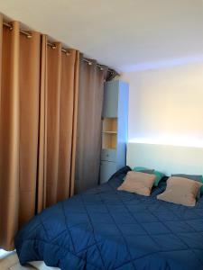 1 dormitorio con cama azul y cortinas en Studio moderne classe 2 dans marina proche mer et etang - lit wifi fibre et parking privé, en Sète