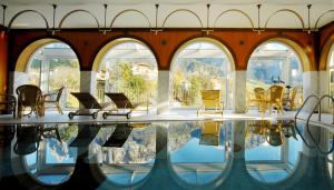 um quarto com uma piscina, cadeiras e janelas em Hotel Rose Wenzer em Vols am Schlern