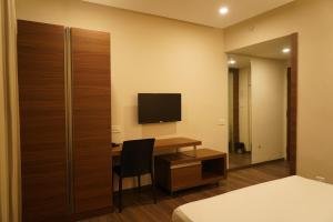 a bedroom with a desk and a television and a bed at Hotel Bekal International in Kāsaragod