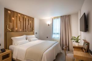 イラクリオン・タウンにあるDimargio Luxury Hotel & Spaの白い大型ベッドとテレビが備わるホテルルームです。