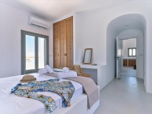 biała sypialnia z 2 łóżkami i oknem w obiekcie Siora of Paros - Ammiralis & Castelis w mieście Nausa