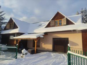 une maison recouverte de neige dans l'établissement Gospodarstwo Agroturystyczne U Stasików, à Spytkowice