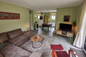 a living room with a couch and a table at De Zingende Wilg, heerlijk huisje met Hottub in Ewijk