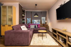 ein Wohnzimmer mit einem lila Sofa und einem TV in der Unterkunft Dufti Home in Plovdiv Center & Old Town / Kapana in Plowdiw