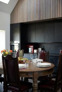 una cocina con mesa de madera con sillas y una cocina con armarios negros en Monkstadt No 10 The Horse Walk, en Totscore