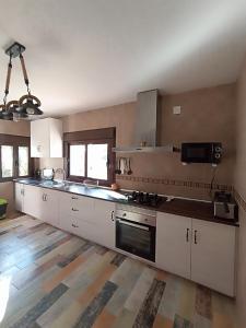 a large kitchen with white cabinets and a stove at Alojamiento Rural Mariola in La Iruela