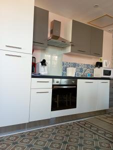 a kitchen with white cabinets and a stove at Maison charmante à Saint-Blimont avec jardin in Saint-Blimont