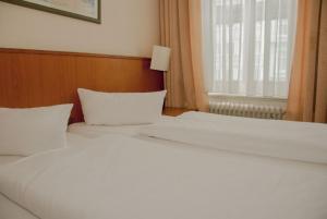 two white beds in a bedroom with a window at Hotel Terminus am Hauptbahnhof in Hamburg