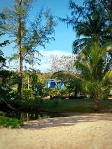 a park with palm trees and a house in the background at Twocans Resort KohMak - SHA in Ko Mak