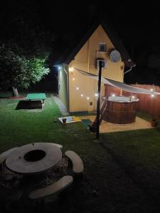 a tent in a yard at night with a pool and a table at DÉZSAFÜRDŐS TÓPARTI NYARALÓ in Gyékényes