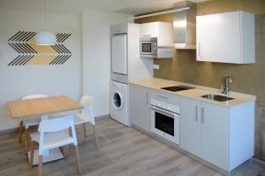 a kitchen with white cabinets and a table and a dining room at APARTAMENTOS TURÍSTICOS GUIANA in Ponferrada