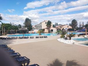 a large swimming pool with chairs and a resort at MOBIL HOME LE PRECIEUX in Valras-Plage