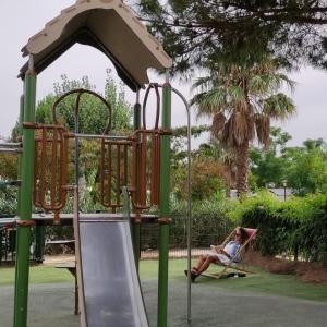 a woman sitting in a hammock on a playground at MOBIL HOME LE PRECIEUX in Valras-Plage