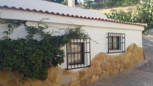 un edificio blanco con ventanas con barrotes y pared de piedra en CASAS CUEVAS ELVIRA, en Hinojares
