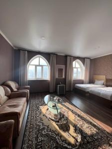 un ampio soggiorno con un letto e un divano di Shah Palace Hotel a Bishkek