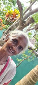 an older woman is standing next to a tree at Wimala B&B in Bentota