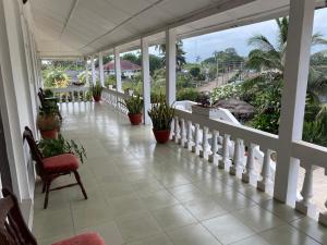 un porche con una silla y macetas. en Casablanca Guest Inn, en Takoradi