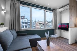 a living room with a couch and a large window at WallStreet, The Luxury Suites in Thessaloniki