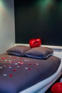 Una cama con corazones y una almohada roja. en ESCAPE ZEN Suite & spa privatif, en Chambly