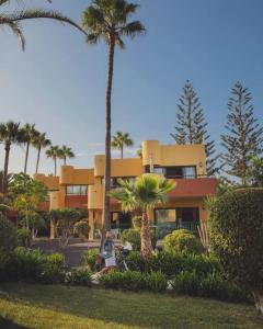 een vrouw die voor een geel gebouw met palmbomen staat bij Blue Pearl in La Oliva