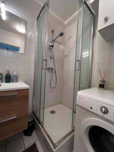 een badkamer met een douche en een wasmachine bij Appart calme avec jardin et parking. 15mn de Paris in Le Bourget
