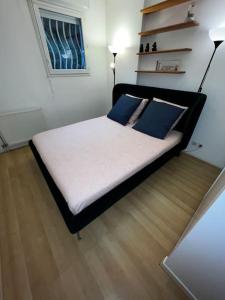 een bed met blauwe kussens in een kamer bij Appart calme avec jardin et parking. 15mn de Paris in Le Bourget