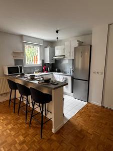 een keuken met een eiland met stoelen en een koelkast bij Appart calme avec jardin et parking. 15mn de Paris in Le Bourget