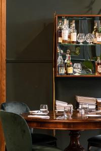 a table with two chairs and a shelf with bottles at Hotel Continentale in Trieste