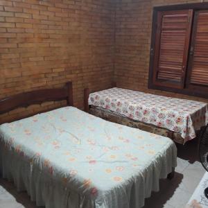 dwa łóżka w pokoju z ceglaną ścianą w obiekcie Sítio Completo, na estrada de Aldeia Velha, com rio a frente da porteira w mieście Silva Jardim