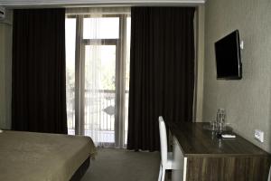 Habitación de hotel con cama y ventana grande en Palma Hotel, en Gagra
