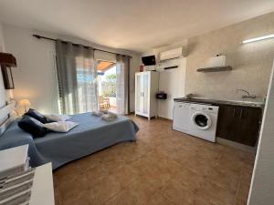 a bedroom with a bed and a kitchen with a washing machine at Estudi Es Carnatge in Playa Migjorn