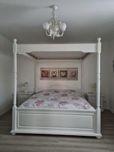 a bedroom with a white bed and a chandelier at Auf der Reuth in Selb