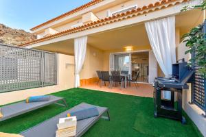 une arrière-cour avec une terrasse entourée d'herbe verte dans l'établissement Luxury Holiday House Tenerife, à Puerto de Santiago