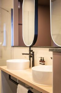 two sinks in a bathroom with two mirrors at Hotel Halbert in Groningen