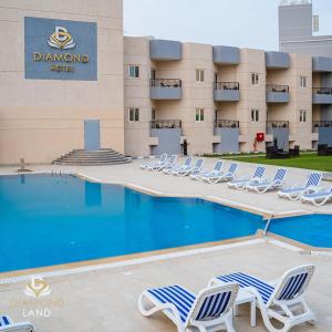a pool with lounge chairs in front of a hotel at Diamond Land Hotel in Madinat Al Ashir min Ramadan