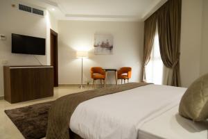 a hotel room with a bed and a table and chairs at Diamond Land Hotel in Madinat Al Ashir min Ramadan
