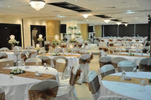 un gran salón de banquetes con mesas y sillas blancas en Caesar Hotel Ramallah, en Ramallah