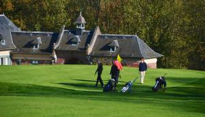 een groep mensen die op een golfbaan lopen bij Le logis des Chênes, superbe bungalow dans quartier résidentiel proche de Namur in Wépion