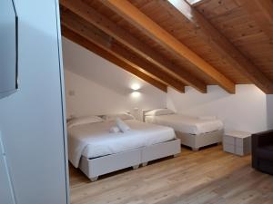 two beds in a room with wooden ceilings at Superior Beach Aparthotel in Lido di Jesolo