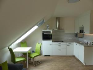 a kitchen with green chairs and a table with a sink at Appartementhaus Zur schönen Aussicht in Bad Abbach