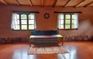 um quarto com uma cama com duas janelas e um tapete em MAMAICUNA CABAÑA em Tilcara
