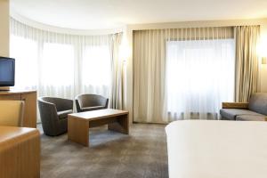 a hotel room with a couch and chairs and a tv at Novotel Gent Centrum in Ghent