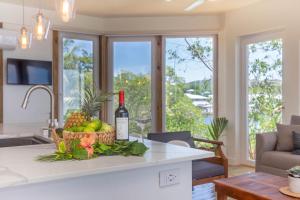 Una botella de vino y una cesta de fruta en la encimera de la cocina. en Wow! Views and more, fantastic 2 bedroom in West End - Villa Agua apts en Roatán