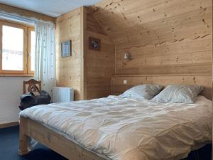 1 dormitorio con 1 cama con pared de madera en Appartement Alpe Huez 8 personnes centre station en LʼHuez